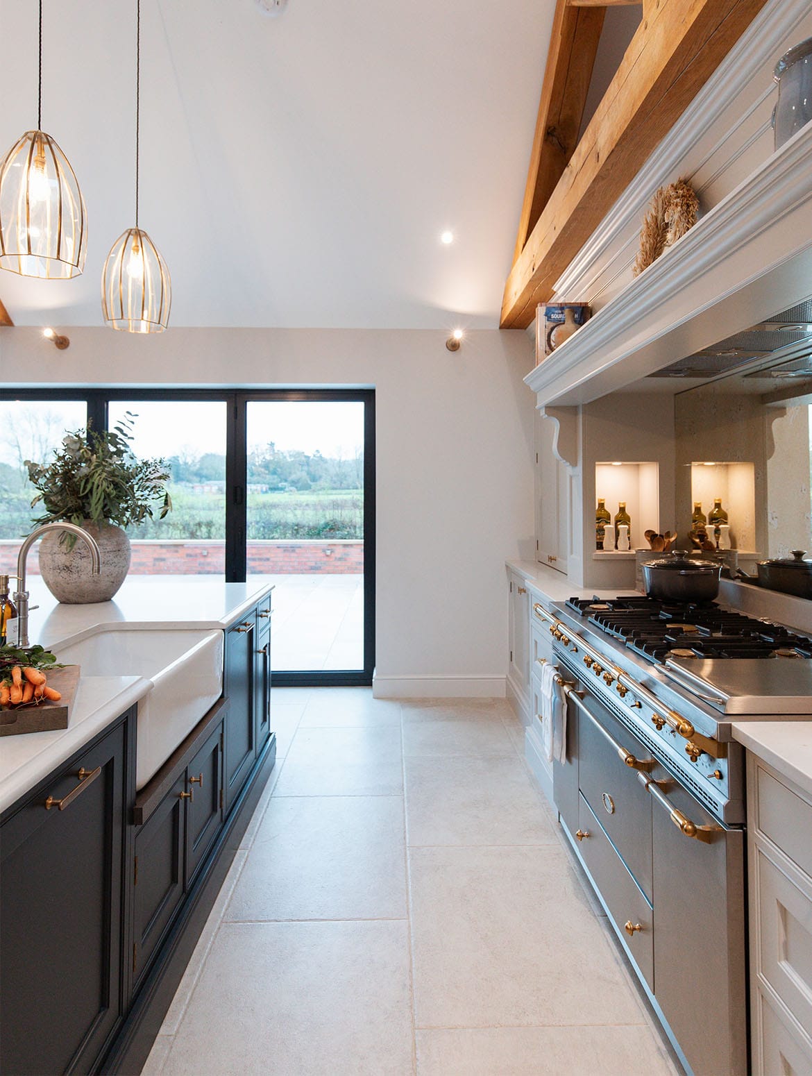 A traditional shaker kitchen in French Grey. The view to the garden through French doors is guided by the off-black island with Quooker tap just visible on one side and a Lacanche Citeaux on the other