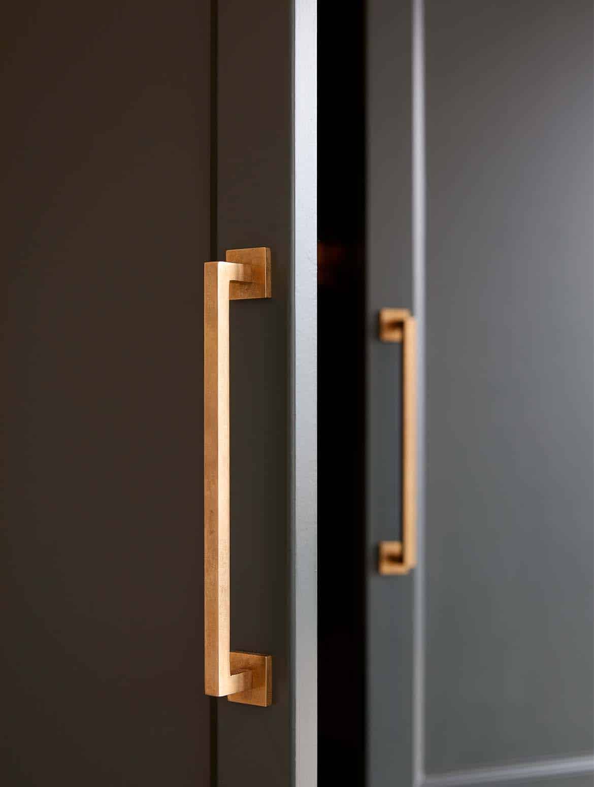 A bespoke bootroom in Studio Green. A close in view of two doors of the bespoke cabinetry. The handles taken from Armac Martin’s Bromsgrove collection contrast well with the Studio Green of the bespoke panelling. 