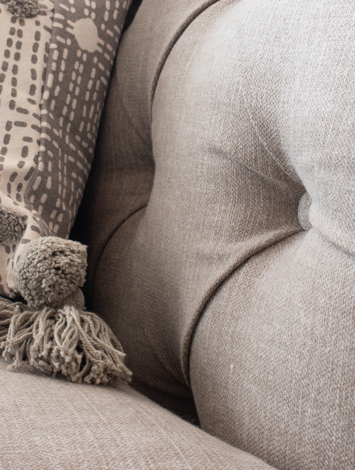 A bespoke media wall in French Grey. A close in on the dimples of the Tetrad sofa where a throw with tasseled ends is draped over the sofa back. 