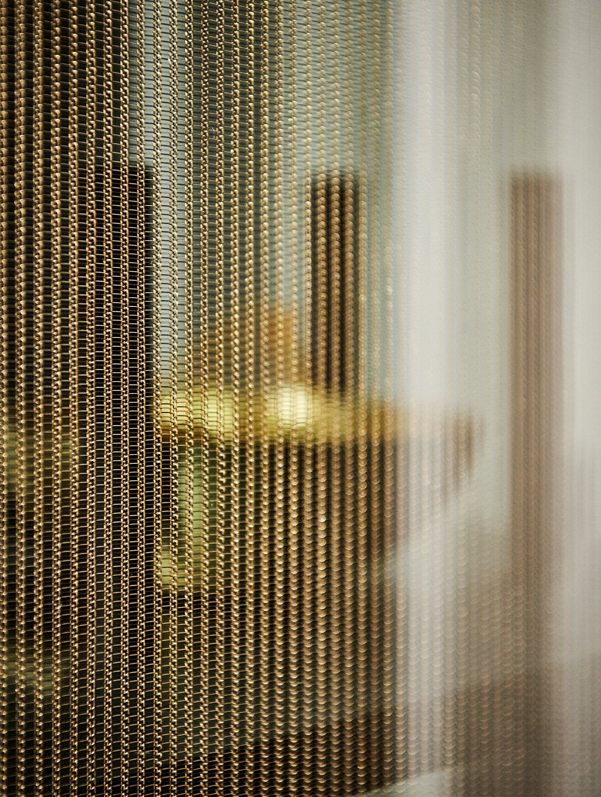 A modern kitchen with quartz-top islands. A close in view of a gold-linked drape over one of the bespoke cabinet doors. 