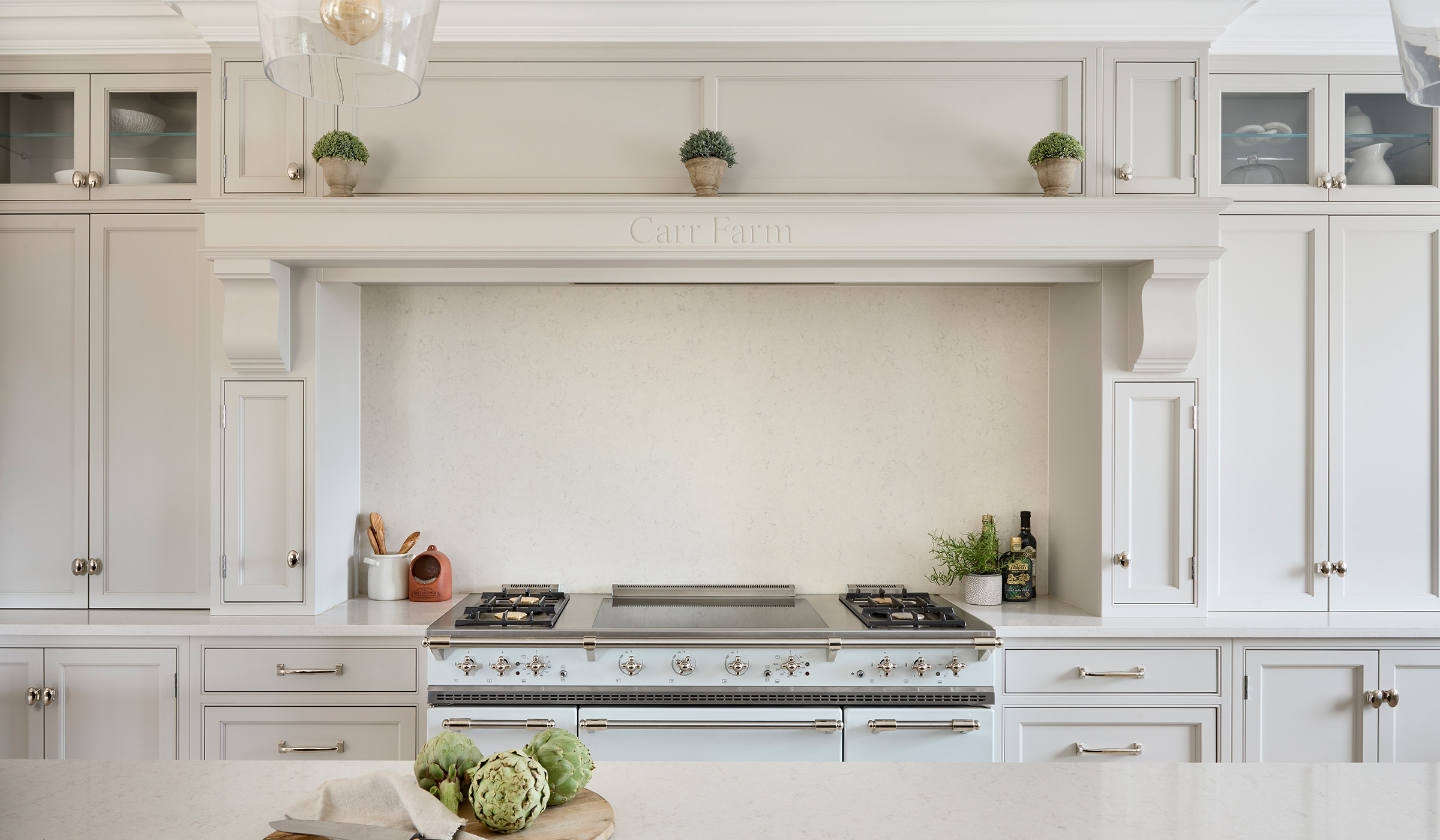 The Carr Farm Traditional Shaker Kitchen Project A traditional shaker kitchen in French Grey. The bespoke cabinetry surrounding the pastel blue Lacanche range cooker is in French Grey with the centrepiece the mantel engraved with Carr Farm. The white worktop is just visible opposite the range cooker.