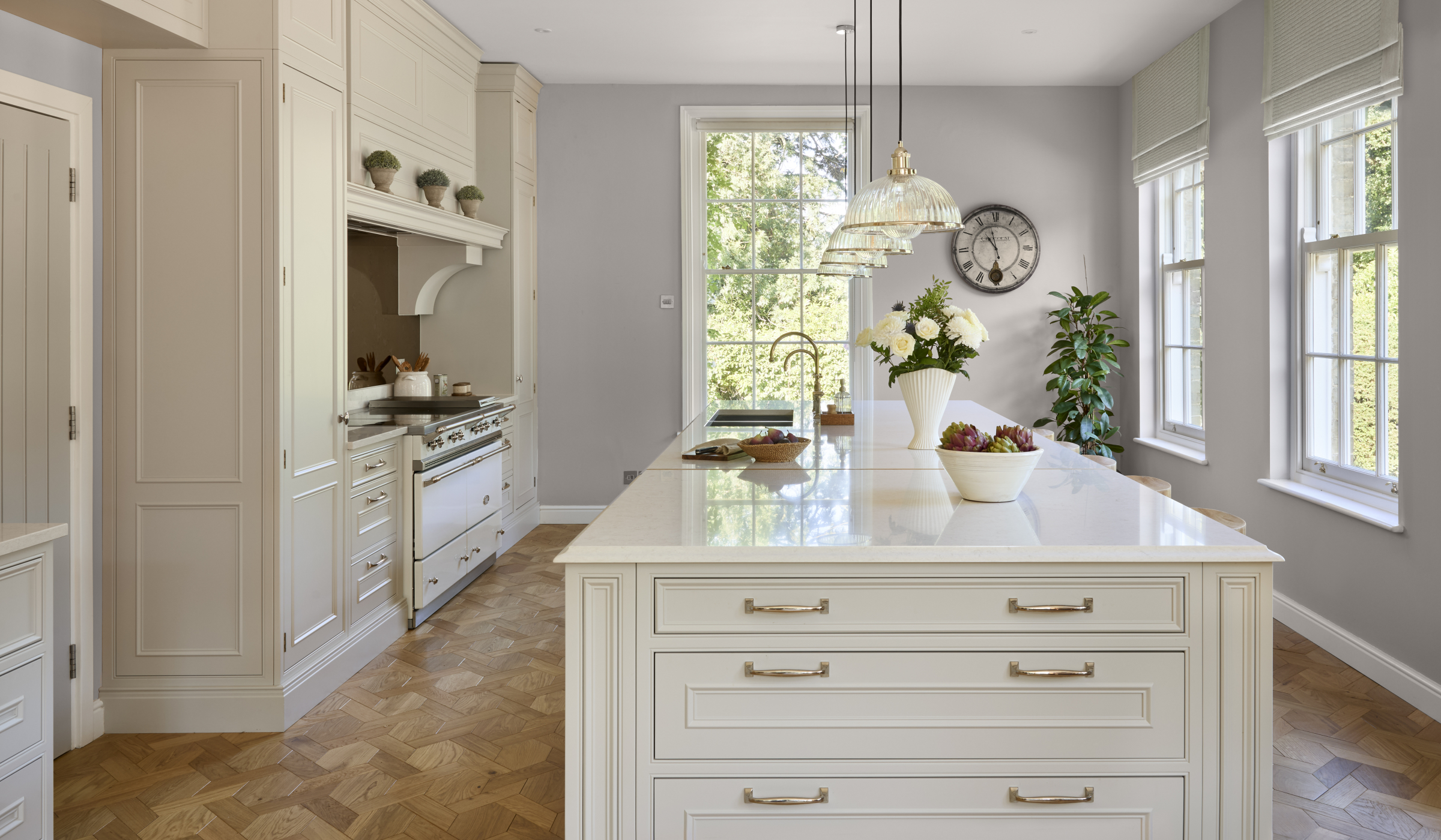 The Rose Garden Traditional Shaker Kitchen Project A traditional cream shaker kitchen with a central island and bespoke cabinetry. The island comprises two Quooker taps and with overhanging lights. Opposite the island, a white Lacanche range cooker stands proud to its surrounding cabinetry.